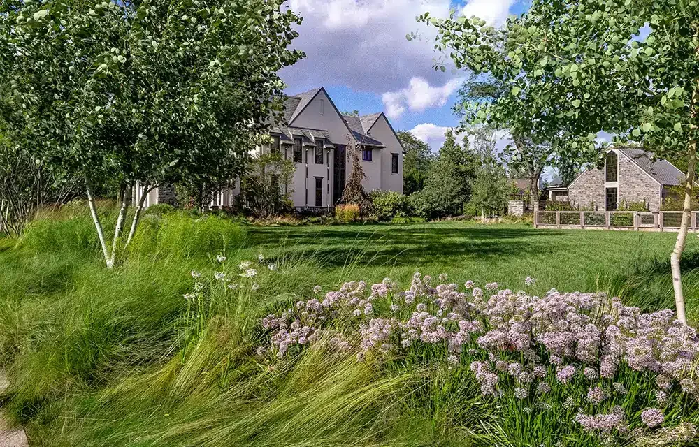 A lawn with grass and flowers in front of a house.