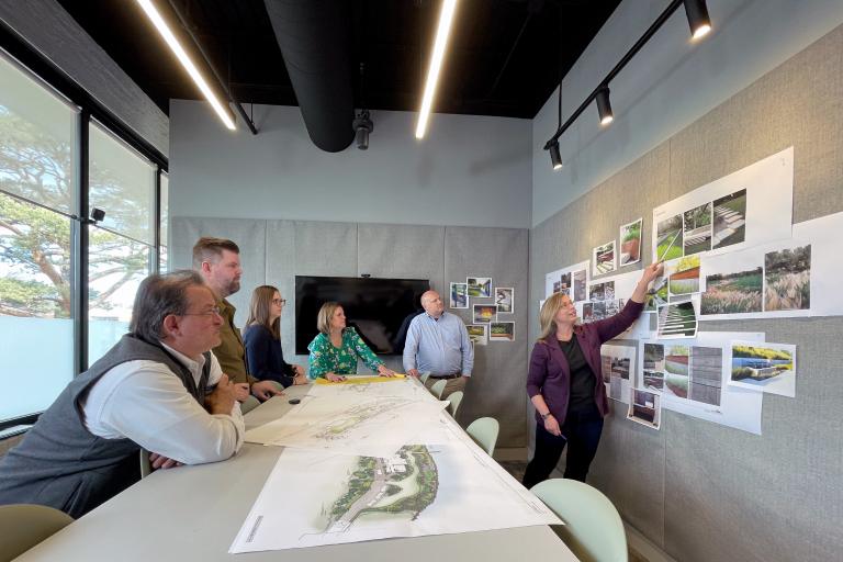 A group of professionals reviewing architectural plans and photos in a modern office setting.