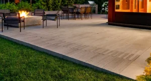Modern patio with outdoor dining table and chairs, fire pit with seating, and surrounding greenery.