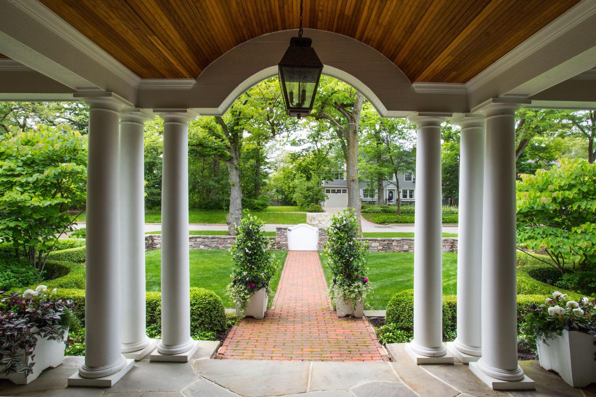 Covered porch with columns overlooking manicured front lawn