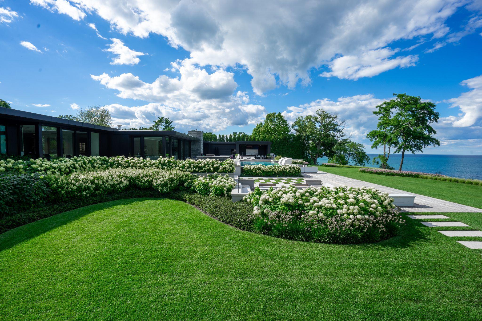 Modern lakefront estate with manicured lawn and white hydrangeas